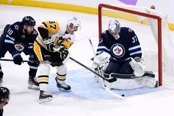 Winnipeg Jets goaltender Connor Hellebuyck makes a save on the Pittsburgh Penguins’ Sidney Crosby during the first period in Winnipeg on Monday. THE CANADIAN PRESS/Fred Greenslade