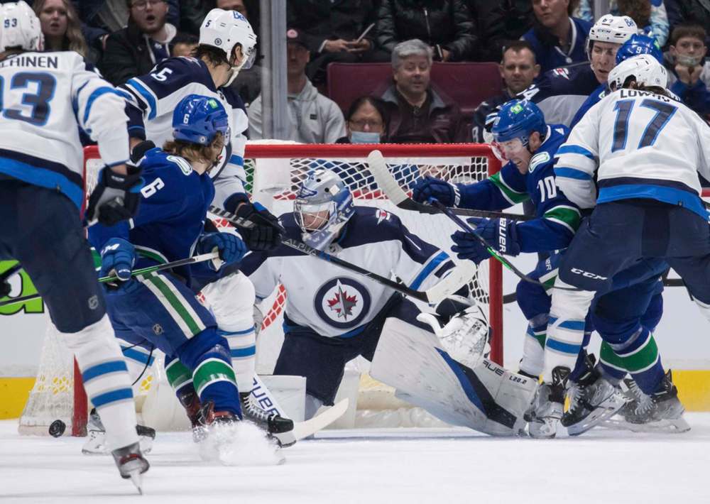 Vancouver Canucks' Tanner Pearson is stopped by Winnipeg Jets goalie Eric Comrie, centre, during the first period. THE CANADIAN PRESS/Darryl Dyck