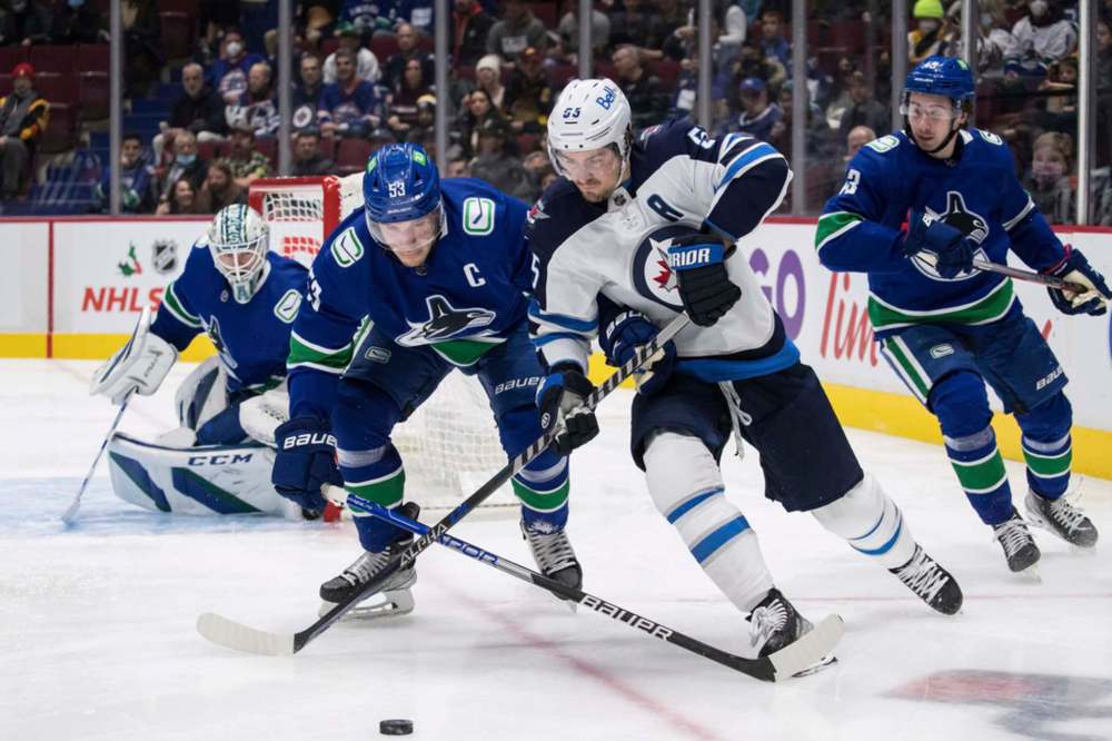Vancouver Canucks' Bo Horvat checks Winnipeg Jets' Mark Scheifele during the first period. THE CANADIAN PRESS/Darryl Dyck