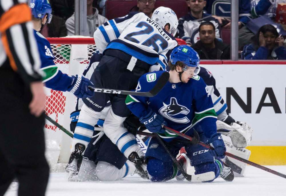 Winnipeg Jets' Blake Wheeler's leg bends sideways at the knee as he vies for the puck against Vancouver Canucks' Vasily Podkolzin, front right, during the third period. Wheeler left the game with an injury and did not return to the ice. THE CANADIAN PRESS/Darryl Dyck