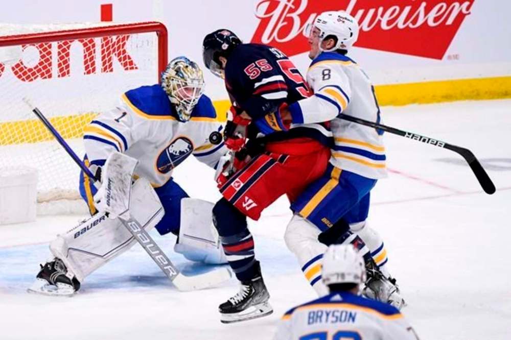 Buffalo Sabres' goaltender Ukko-Pekka Luukkonen keeps his eyes on the puck as Robert Hagg defends against Winnipeg Jets' Mark Scheifele during the first period in Winnipeg on Tuesday. THE CANADIAN PRESS/Fred Greenslade