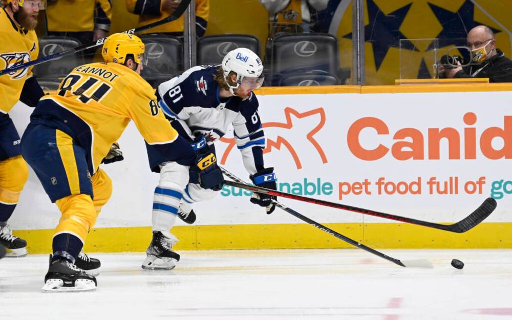 Nashville Predators left wing Tanner Jeannot and Winnipeg Jets left wing Kyle Connor reach for the puck during the first period. (AP Photo/Mark Zaleski)