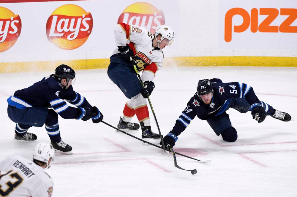 Florida Panthers’ Anton Lundell passes the puck between Winnipeg Jets’ Neal Poink and Dylan Samberg during the first period in Winnipeg on Tuesday. THE CANADIAN PRESS/Fred Greenslade