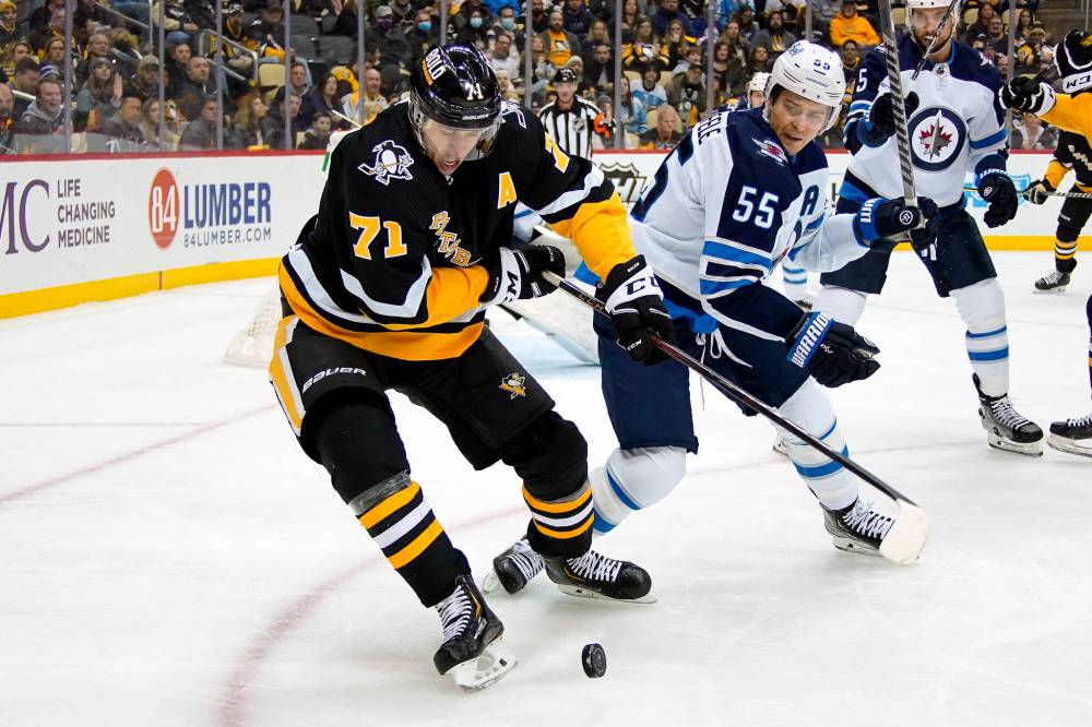 Pittsburgh Penguins’ Evgeni Malkin controls the puck with Winnipeg Jets’ Mark Scheifele defending during an NHL hockey game in Pittsburgh, Sunday, Jan. 23, 2022. (AP Photo/Gene J. Puskar)