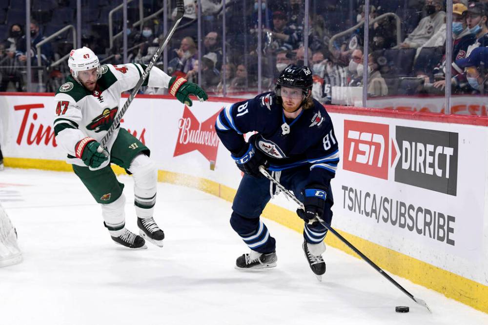 Winnipeg Jets’ Kyle Connor looks to make a pass as Minnesota Wild’s Alex Goligoski pursues him during the second period. THE CANADIAN PRESS/Fred Greenslade