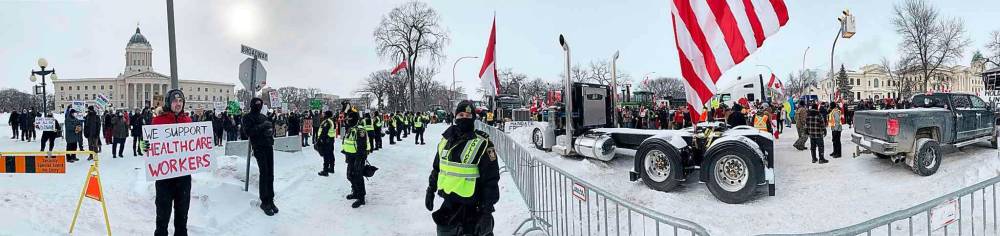 Uniformed police officers formed a line to separate two groups of protesters at the legislature Saturday. (David Lipnowski / Winnipeg Free Press)