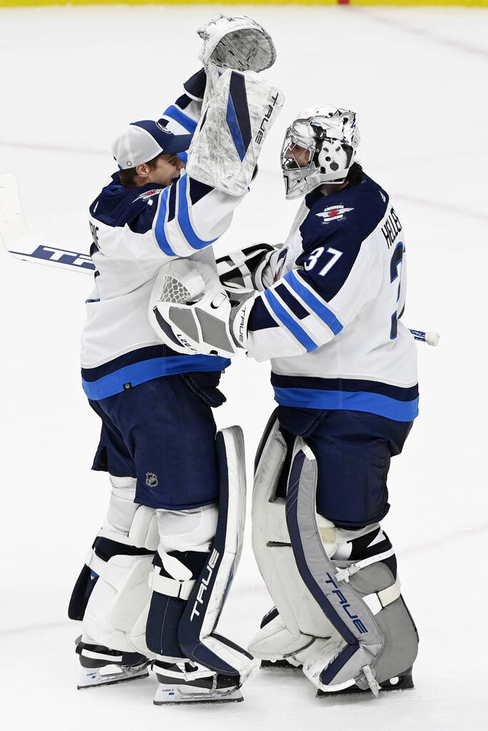 Goalies Eric Comrie (left) and Connor Hellebuyck celebrate Saturday’s win. (Mark Zaleski / The Associated Press files)