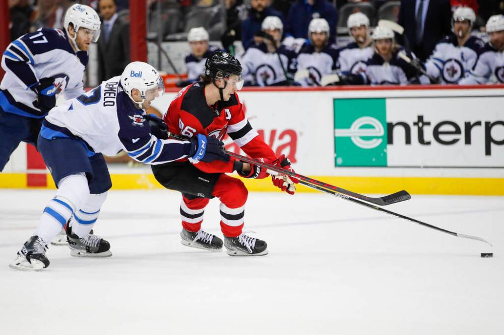 New Jersey Devils centre Jack Hughes fights for the puck against Winnipeg Jets defence Dylan DeMelo during the first period. (AP Photo/Eduardo Munoz Alvarez)
