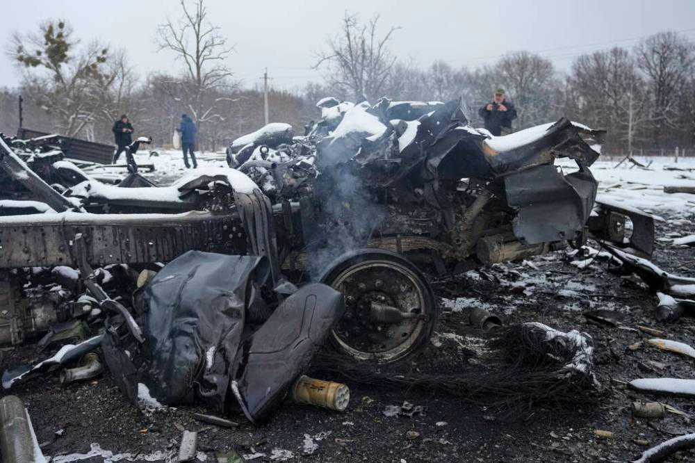 People take photos of still smoldering destroyed Russian military vehicles on the outskirts of Kharkiv, Ukraine, Friday, Feb. 25, 2022. Russian troops bore down on Ukraine's capital Friday, with gunfire and explosions resonating ever closer to the government quarter, in an invasion of a democratic country that has fueled fears of wider war in Europe and triggered worldwide efforts to make Russia stop. (AP Photo/Vadim Ghirda)