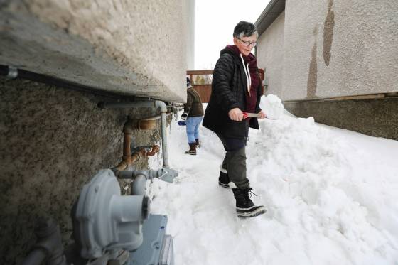RUTH BONNEVILLE / WINNIPEG FREE PRESS Yana Sigurdson and her son Zach remove snow near their foundation to try to keep their basement dry during the spring melt after heavy snowfall this winter.