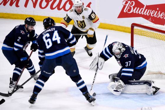 Winnipeg Jets goaltender Connor Hellebuyck covers up the loose puck as Vegas Golden Knights’ Jonathan Marchessault looks for the rebound while Dylan DeMelo and Logan Stanley defend during the first period in Winnipeg on Tuesday. THE CANADIAN PRESS/Fred Greenslade