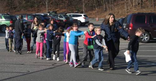 Shannon Hicks / The Associated Press files 
In this December 2012 photo, state police lead a line of children to safety from the Sandy Hook Elementary School in Newtown, Conn., after 20 first-graders and six teachers were killed.
