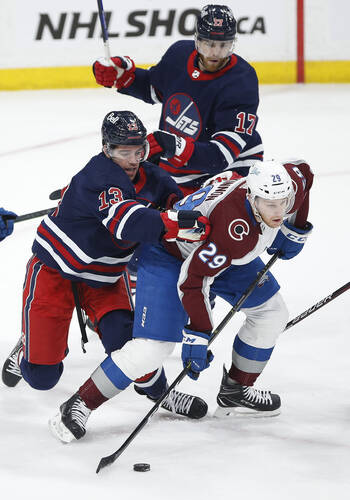 Winnipeg Jets’ Zach Sanford nd Adam Lowry try to stop Colorado Avalanche’s Nathan MacKinnon during the first period. THE CANADIAN PRESS/John Woods