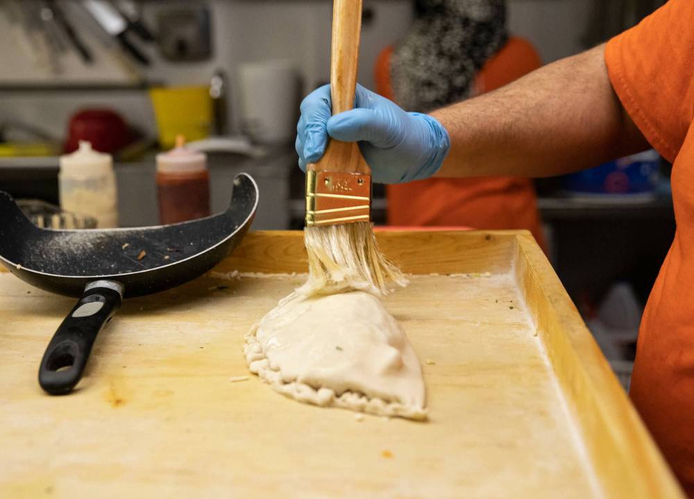 Badis employs a master touch while creating a pita pie. (Jessica Lee / Winnipeg Free Press)