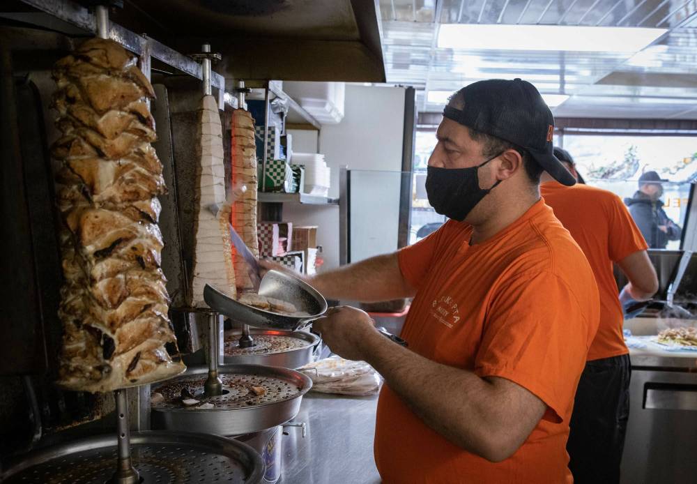 Badis Maymoni carves chicken slices from the spinning spit. (Jessica Lee / Winnipeg Free Press)