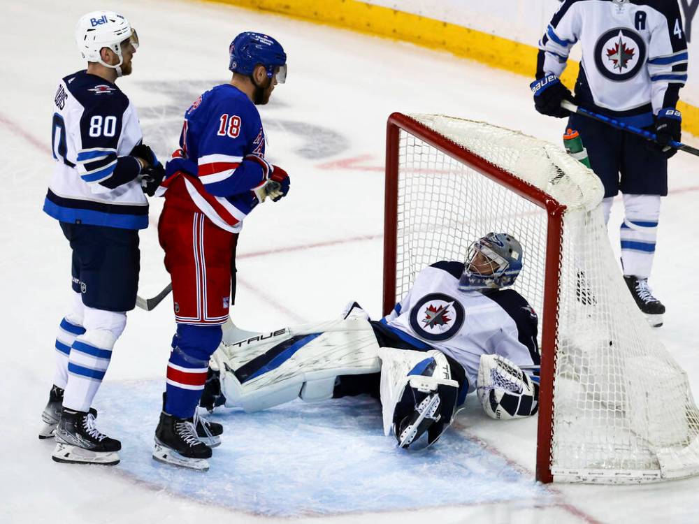 Winnipeg Jets goaltender Eric Comrie falls into the net as Jets left wing Pierre-Luc Dubois and New York Rangers centre Andrew Copp look on during the third period Tuesday in New York. (AP Photo/Jessie Alcheh)