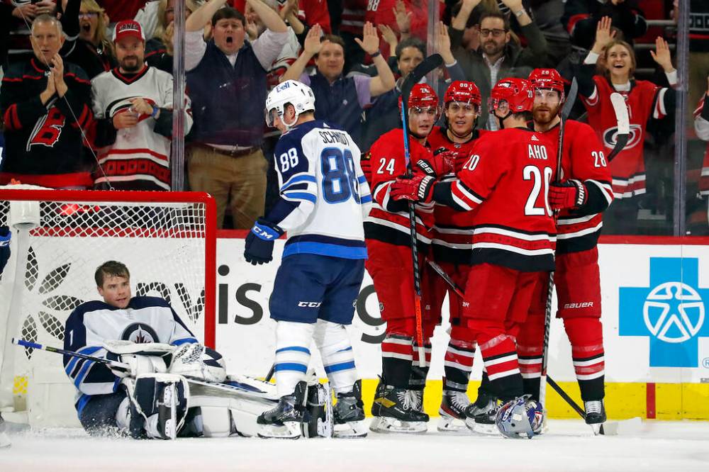 Carolina Hurricanes’ Seth Jarvis celebrates his goal with teammates as Winnipeg Jets’ Nate Schmidt stands near goaltender Eric Comrie during the third period. (AP Photo/Karl B DeBlaker)