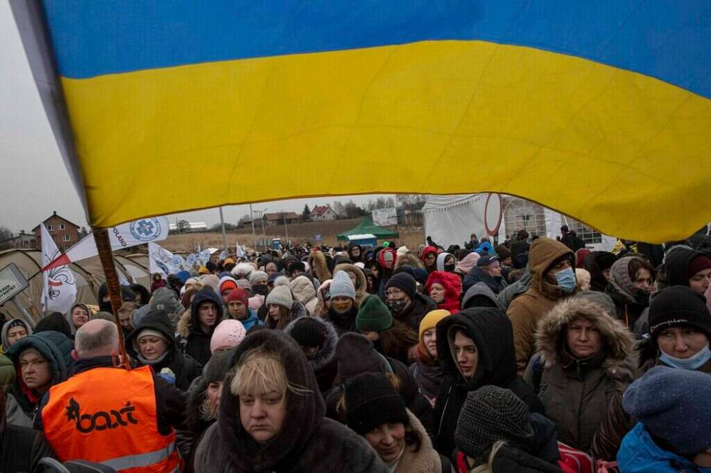 VISAR KRYEZIU / ASSOCIATED PRESS PHOTO
A Ukrainian volunteer Oleksandr Osetynskyi, 44, holds a the country’s flag and directs hundreds of refugees after fleeing from the Ukraine and arriving at the border crossing in Medyka, Poland.