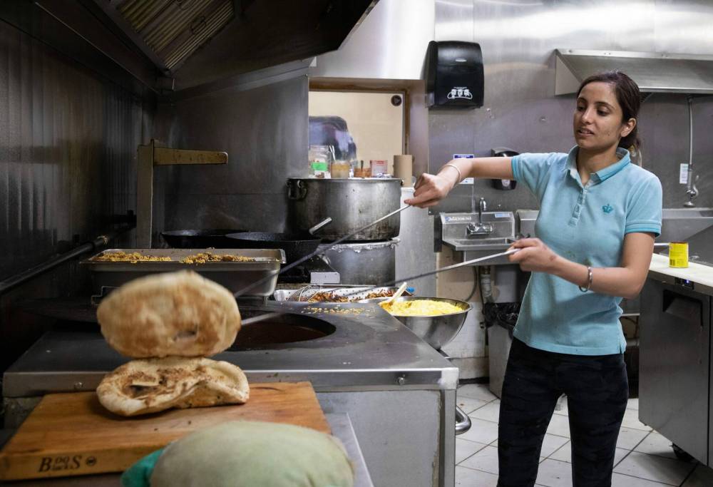 Amandeep Kaur, a worker at Barbeque Hut removes naan from the oven. (Jessica Lee / Winnipeg Free Press)