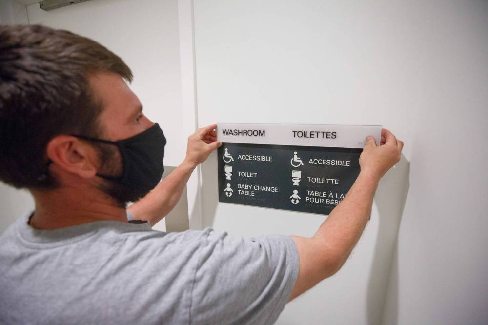 MIKE DEAL / WINNIPEG FREE PRESS
SignEX’s Blair Meyers attaches new signage as the Canadian Museum for Human Rights does away with “men’s” and “women’s” bathrooms.