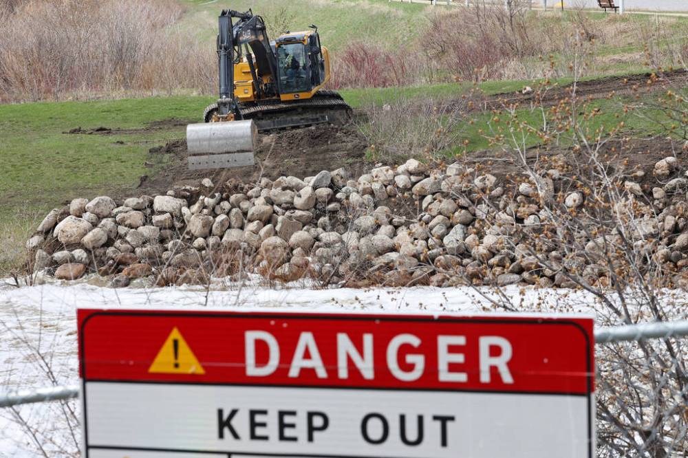 TIM SMITH / THE BRANDON SUN
Workers add large rocks to the eroding shoreline of the Little Saskatchewan River at the Minnedosa dam to shore it up as water levels continue to rise on Tuesday.