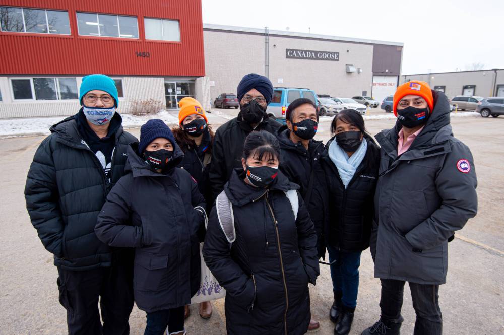 Mike Sudoma / Winnipeg Free Press Union organizers (left to right) Allan Mendoza, Mary Jane Quierre, Mildred Caldo, Manmohan Sidhu, Yolanda Obermaier, Andres Garcia, Rabin Syed, Aseem Saraswat, celebrate outside of Canada Goose Thursday afternoon.