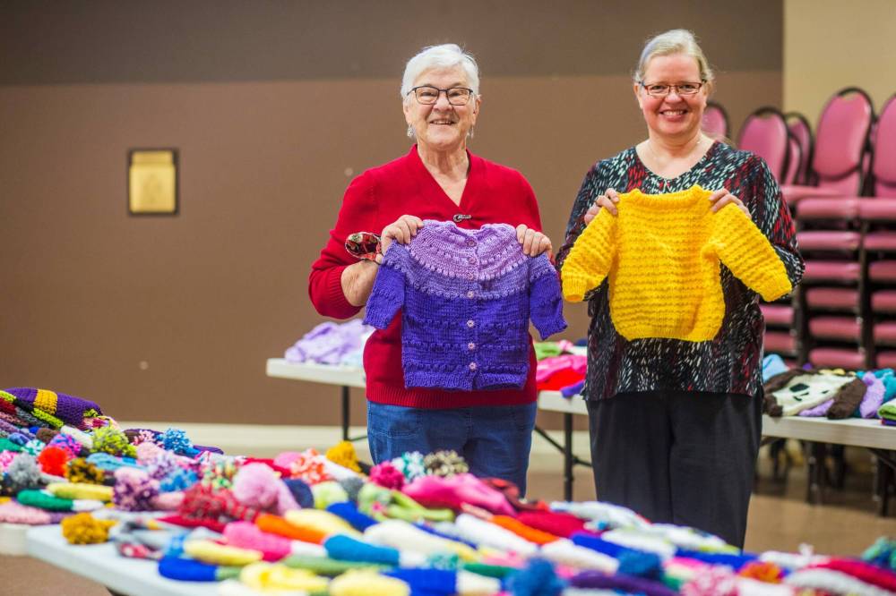 MIKAELA MACKENZIE / WINNIPEG FREE PRESS
Margaret Young, long-time knitting volunteer (left), and Janet Ammeter, church office administrator (who helps with yarn distribution and such), with the knitting gathered for the Christmas Cheer Board at Charleswood United Church in Winnipeg on Thursday.