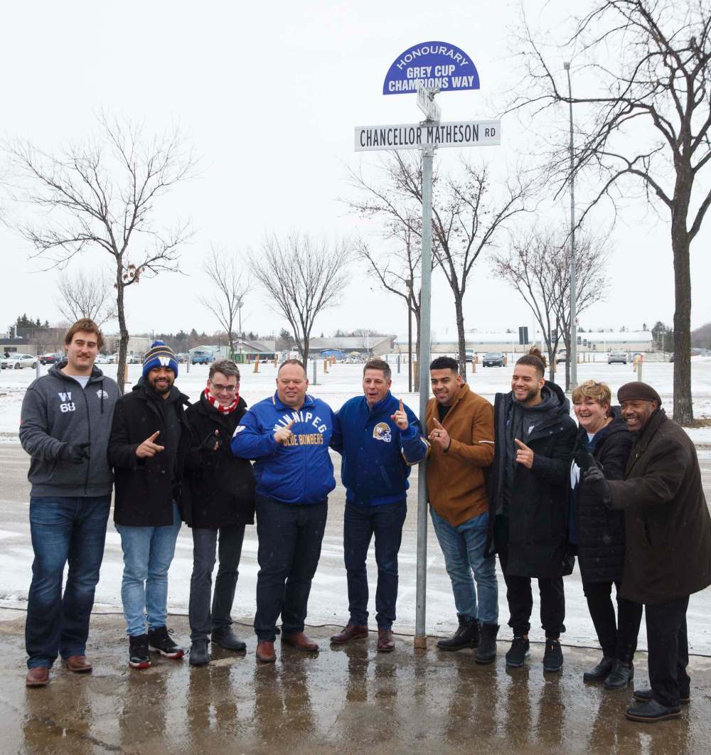 Winnipeg Mayor Brian Bowman (centre), Wade Miller (left of Bowman), president of the Winnipeg Football Club, Andrew Harris (right of Bowman), other Bombers players and executives unveiled an honorary sign, Grey Cup Champions Way, on Friday. (Mike Deal / Winnipeg Free Press)