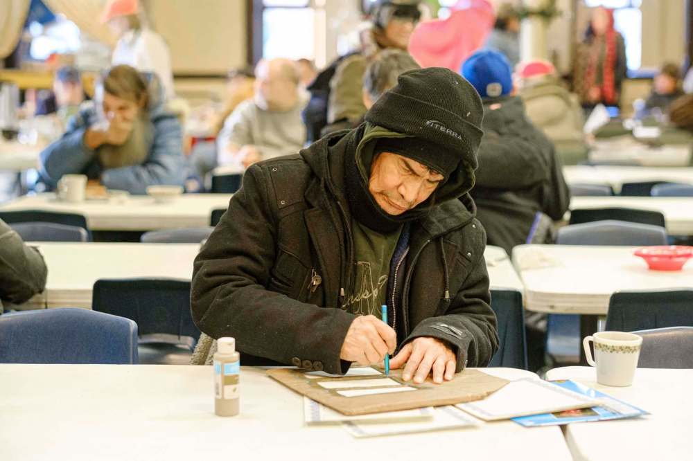 Mike Sudoma / Winnipeg Free Press
Roland, a guest at Wednesday afternoon’s Oak Table program hosted in the Augustine United Church building, works on some of his artwork after getting some lunch.