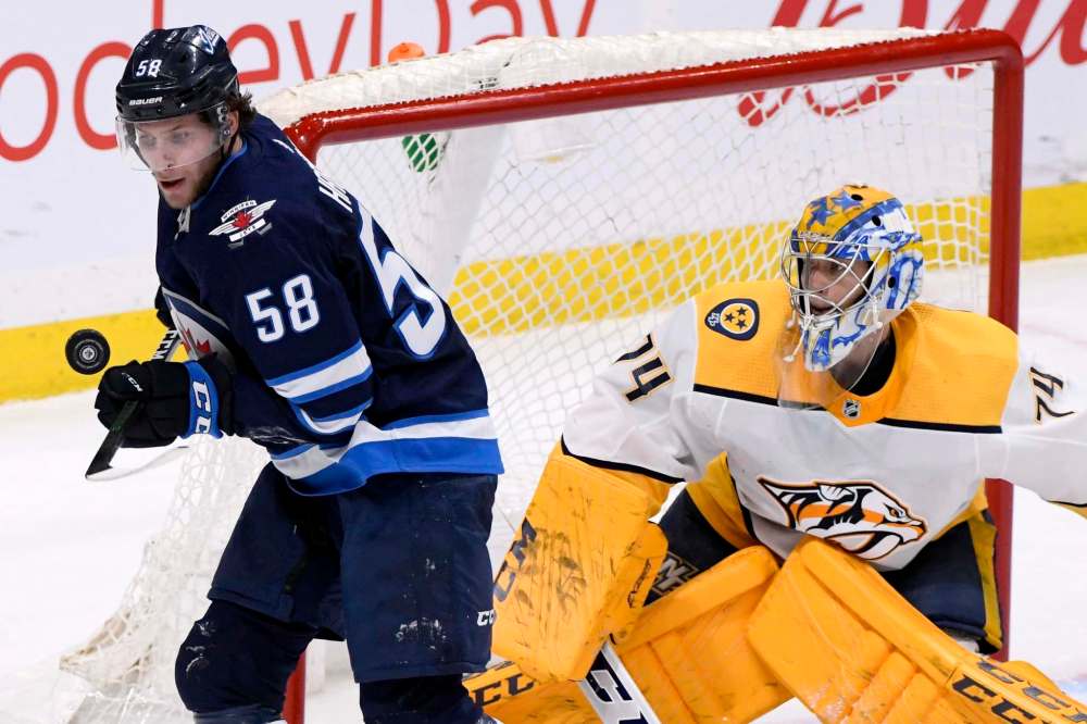 THE CANADIAN PRESS/Fred Greenslade
Winnipeg Jets' Jansen Harkins works to control a bouncing puck in front of Nashville Predators goaltender Juuse Saros during the third period in Winnipeg on Tuesday. The game marked the first time Harkins' father Todd had seen his soon play in the NHL in person.