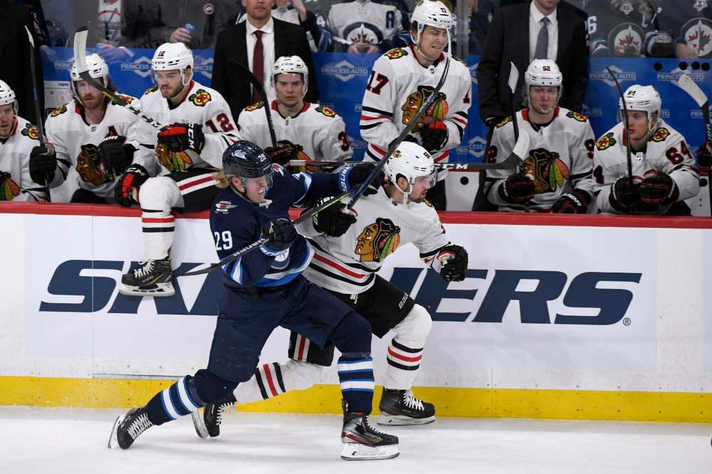 Winnipeg Jets' Patrik Laine (29) checks Chicago Blackhawks' Erik Gustafsson (56) in front of the Blackhawks bench during first period NHL action in Winnipeg on Sunday. Feb. 16, 2020. THE CANADIAN PRESS/Fred Greenslade