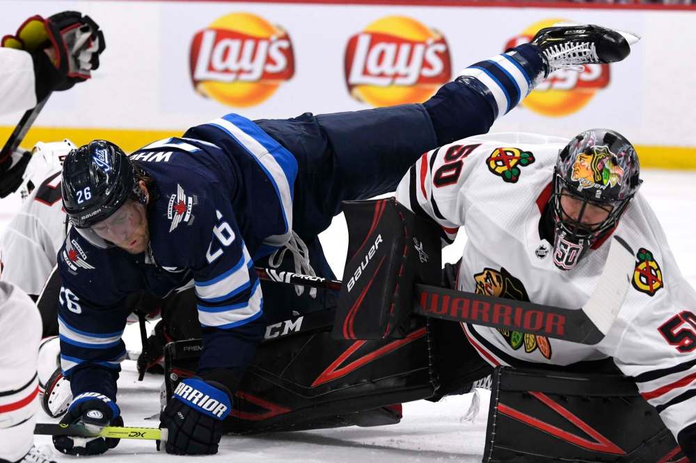 Winnipeg Jets' Blake Wheeler (26) falls over Chicago Blackhawks' goaltender Corey Crawford (50) during second period NHL action in Winnipeg on Sunday, Feb. 16, 2020. THE CANADIAN PRESS/Fred Greenslade