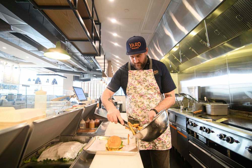 Mike Sudoma / Winnipeg Free Press
Yard Sale/Good Fight Tacos kitchen manager Steven Toews doles out some fries to go along with the 342 Burger.