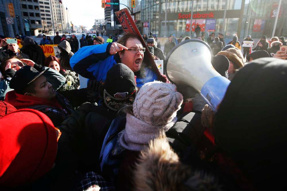 JOHN WOODS / WINNIPEG FREE PRESS
An unidentified person, centre, speaks out against protesters who closed Portage and Main to traffic Wednesday is surrounded.