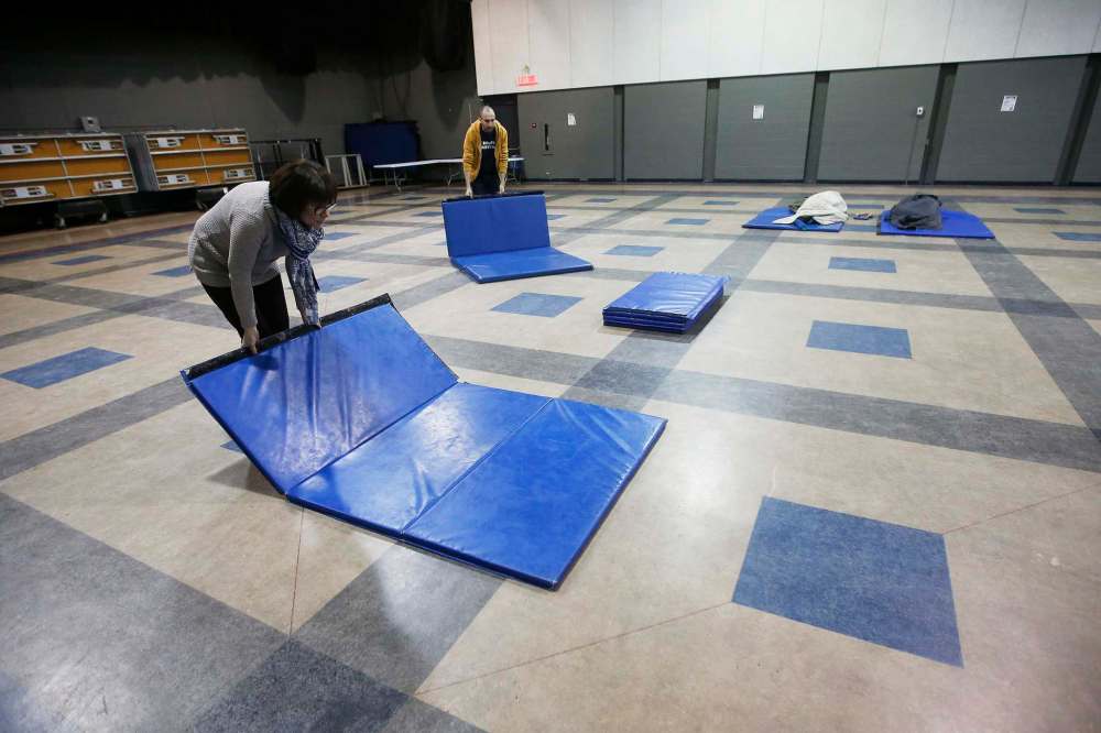 Marion Willis, executive director of St. Boniface Street Links, and volunteer co-ordinator Robert Lidstone set up sleeping mats in the Franco Manitoban Cultural Centre on Monday in preperation for the new shelter. (John Woods / Winnipeg Free Press files)