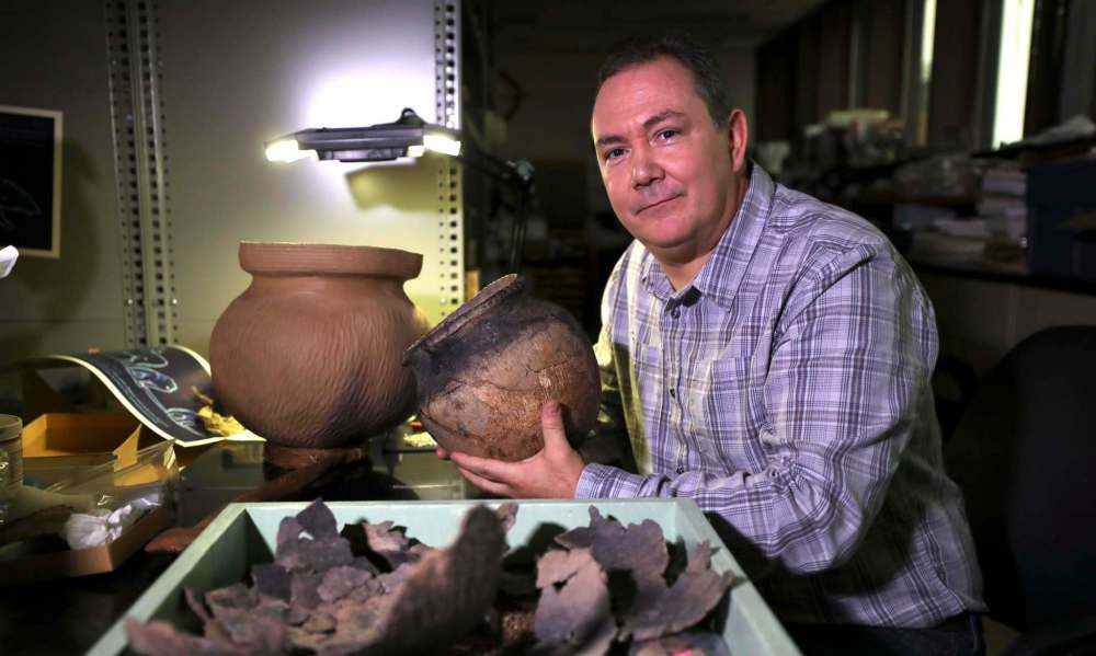 RUTH BONNEVILLE / WINNIPEG FREE PRESS FILES
Manitoba Museum curator of archeology Kevin Brownlee with pieces of pottery from the time when a peace treaty was signed at The Forks in or around the year 1285.