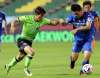 Jeonbuk Hyundai Motors FC's Kim Jin-su, left, fights for the ball against Suwon Samsung Bluewings's Park Dae-won during the opening game of South Korea's K-League football match at the Jeonju World Cup Stadium in Jeonju, South Korea, Friday. (Na Bo-bae/Yonhap via AP)