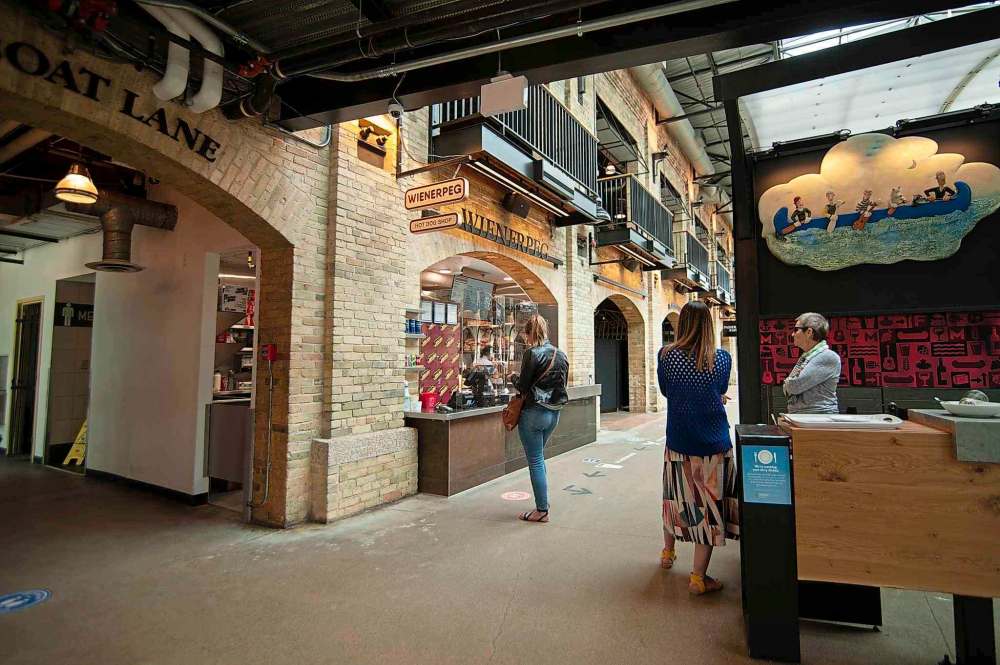 A customer waits for their order at Weinerpeg inside of The Forks Market Saturday afternoon, a day after The Forks re-opened for a soft launch after being closed for nearly two months. (Mike Sudoma / Winnipeg Free Press)