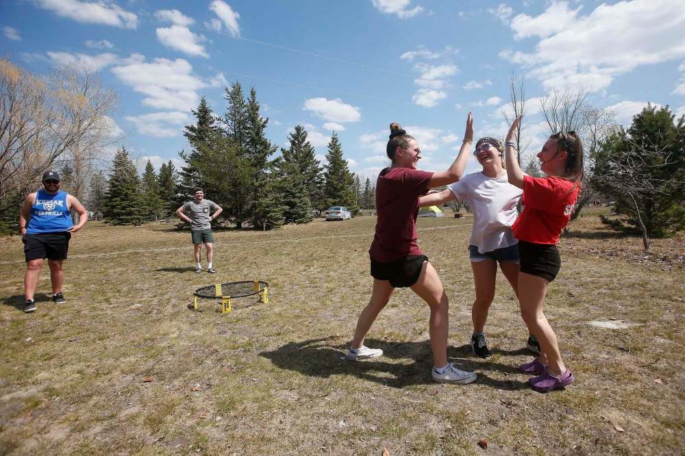 Sara Scholefield (from left), Jessica Popowich and Kelsey Weibe high-five each other as they celebrate after defeating their male friends Jonathan Bennett, Zach Wood and Domenic Horvath in a game of spike ball at Birds Hill park Sunday. John Woods / Winnipeg Free Press