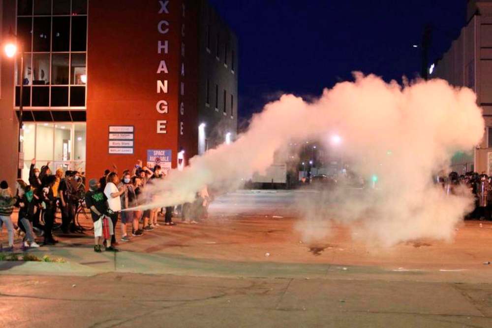 A protester triggers a fire extinguisher toward police officer during Saturday night's riot in downtown Fargo. C.S. Hagen / Fargo Forum