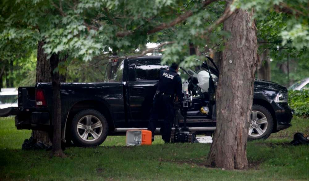 An RCMP police officer looks in the cab of a pickup truck on the grounds of Rideau Hall in Ottawa, Thursday. THE CANADIAN PRESS/Adrian Wyld