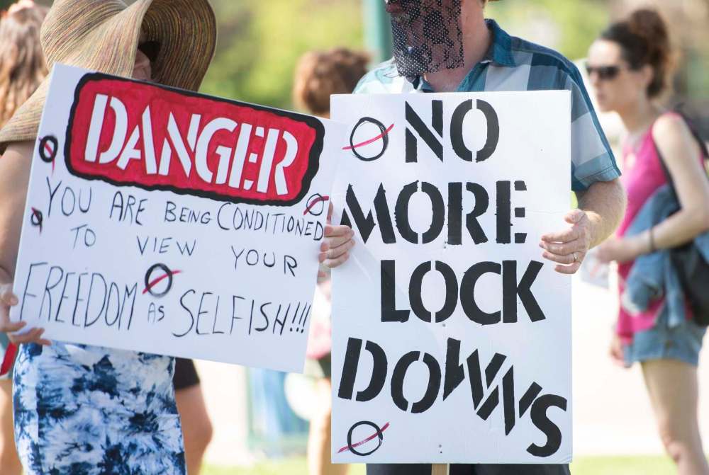 Mike Sudoma / Winnipeg Free Press
Demonstrators hold signs during a rally against the continued pandemic-related public health orders Saturday at the Manitoba legislature.