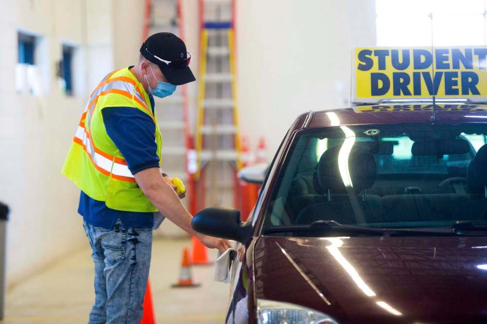 MIKAELA MACKENZIE / WINNIPEG FREE PRESS
Examiner Yuri Yermilov sanitizes the car before going on a driving test in Winnipeg on Wednesday.