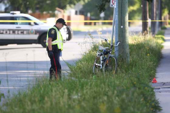 MIKE DEAL / WINNIPEG FREE PRESSA Winnipeg police officer surveys the scene near Moncton Avenue and Grey Street after a cyclist was injured in a hit-and-run. The 50-year-old man died later in hospital.