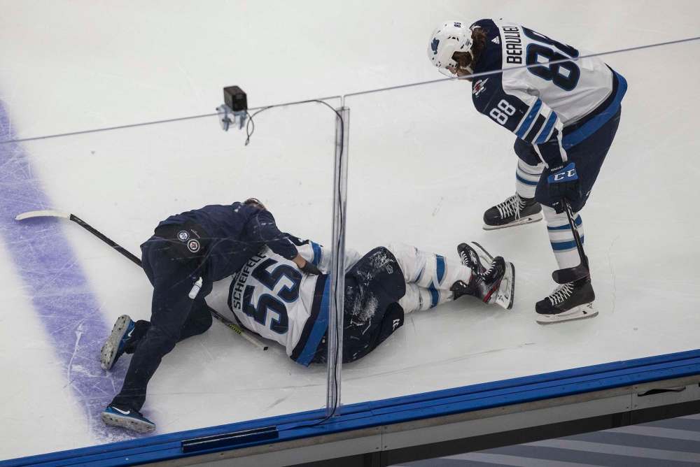 Winnipeg Jet Mark Scheifele is helped after being injured as teammate Nathan Beaulieu (88) looks over him against the Calgary Flames during first period NHL qualifying round game action in Edmonton Saturday. Jason Franson / The Canadian Press