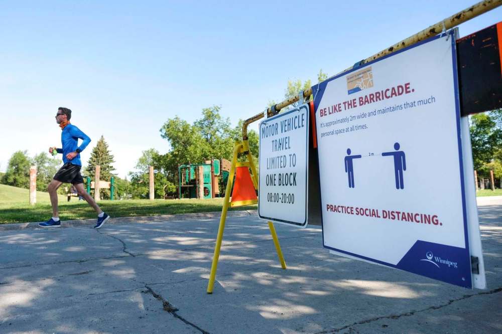Daniel Crump / Winnipeg Free Press
A runner passes a barricade on Vialoux Drive Saturday reminding motorists vehicular traffic is limited to one block. Vialoux Drive is one of 10 city streets that has been part of the Open Streets initiative.