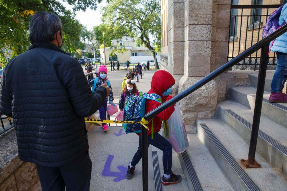 Mike Deal / Winnipeg Free Press
Young students, donning masks and practising social distancing, enter Principal Sparling School Tuesday morning on the first day back to school.