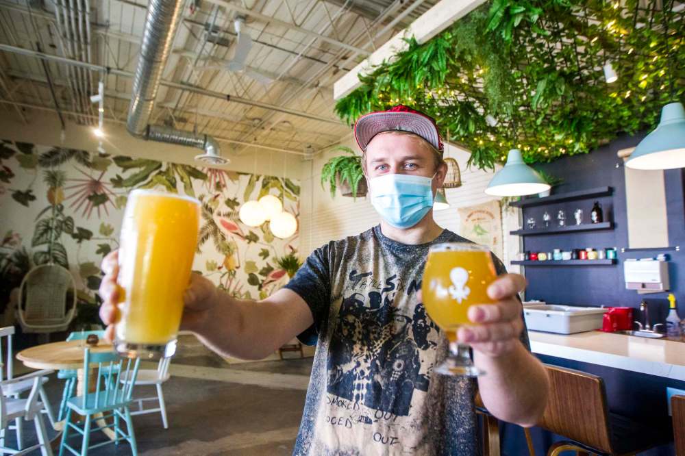 Kilter taproom manager Mischa Decter with a Waves pale ale and a Juicii IPA at the St. Boniface brewery, where masks are mandatory. (Mikaela MacKenzie / Winnipeg Free Press)