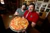 Alfonso Maury, owner of Corrientes pizzeria and La Pampa empanada shop, and his son Ivo show off a Las Cuartetas pizza at his pizzeria. Maury developed the restaurant&rsquo;s original recipes. (John Woods / Winnipeg Free Press)