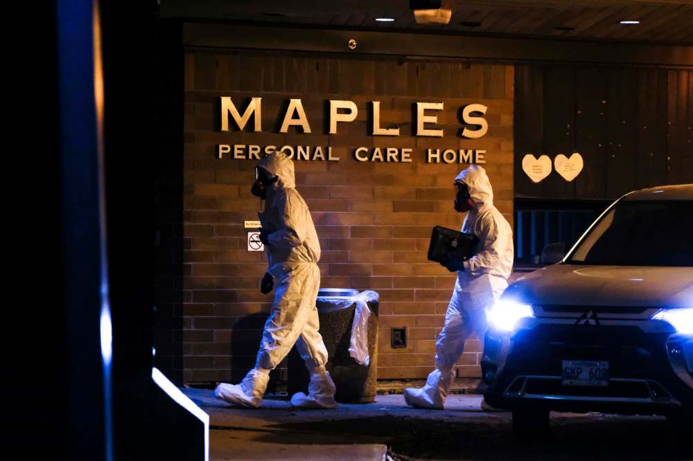 Members of the Winnipeg Police Identification Unit dressed in protective equipment enter Maples Personal Care Home on Saturday night. (Daniel Crump / Winnipeg Free Press)
